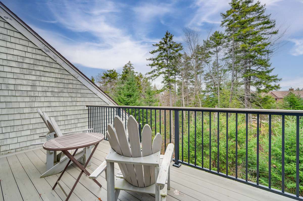 Deck of a ski-in/ski-out chalet near Bretton Woods with mountain views and Adirondack chairs
