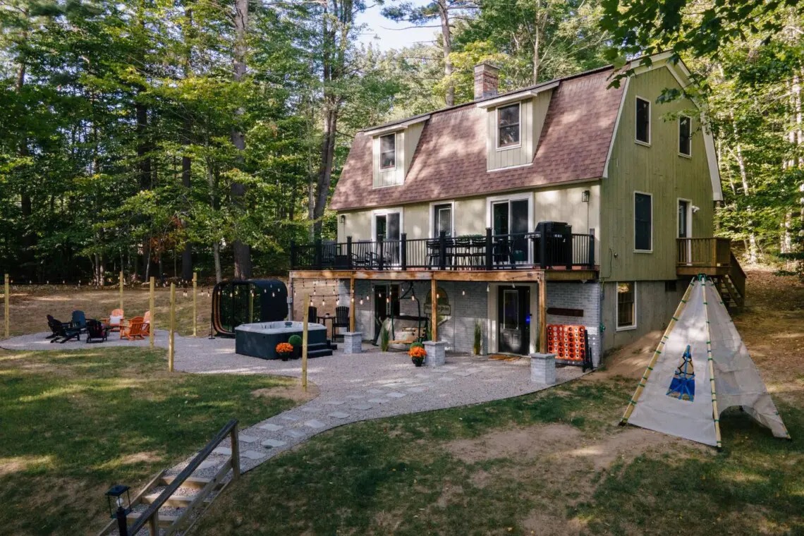 Peak and Pine Retreat in Bartlett, New Hampshire — daytime exterior showing the house, deck, hot tub, fire pit, and outdoor living area